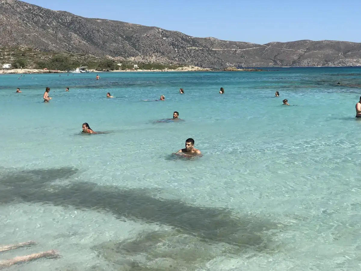 Swimmers in the shallow turquoise lagoon at Elafonisi Beach, Crete