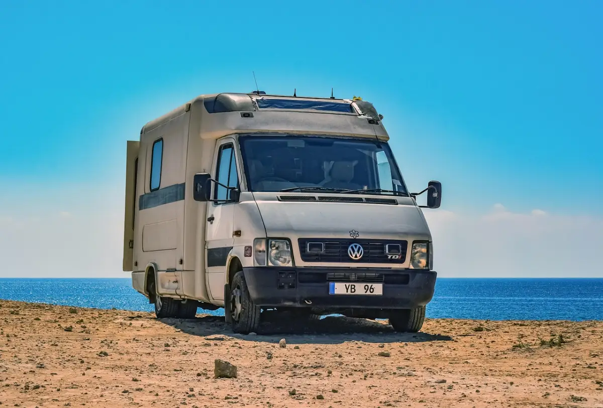 RV parked on a sandy shore beside the sea