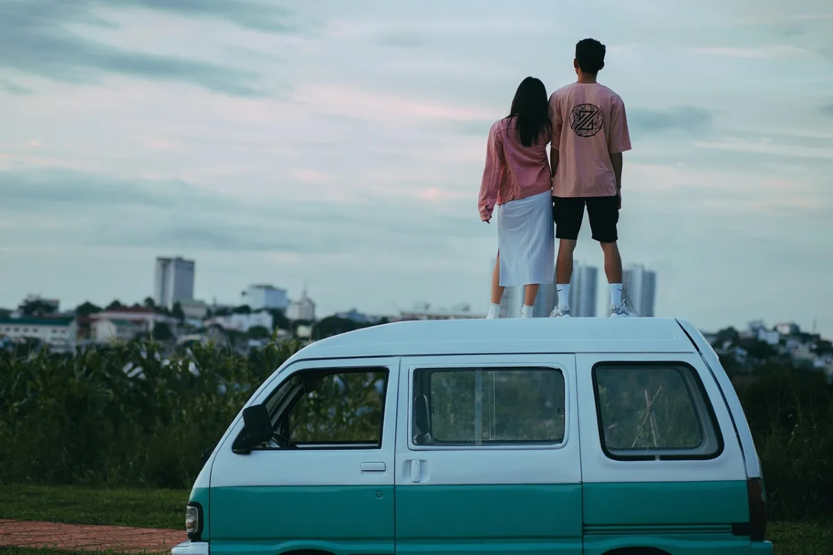Couple standing on a camper van looking out over a city skyline