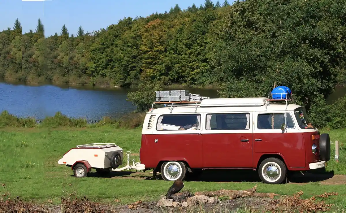 Red VW camper van parked beside a lake, a free overnight parking spot on public land