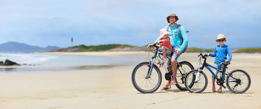 Family with bikes on a beach, a land-based alternative to a Galapagos cruise