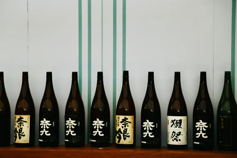 Row of Japanese sake bottles, like the collection at In Between Days sake bar