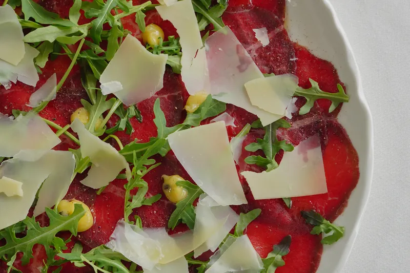 Beef carpaccio with arugula and parmesan, like the Wagyu carpaccio at Juno & The Peacock