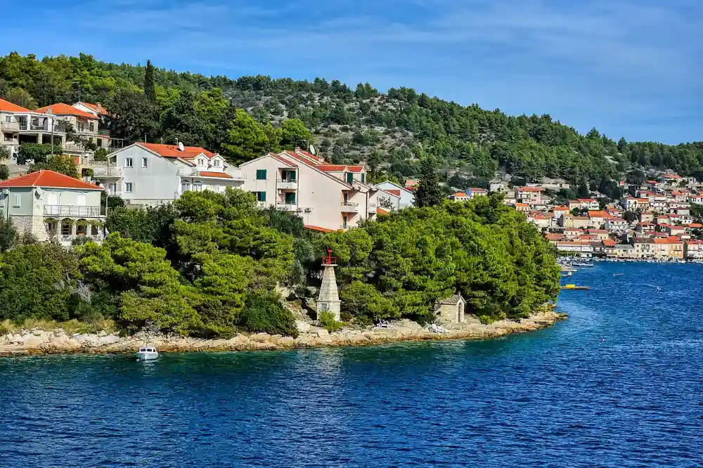 Waterfront edge of Korcula Town with red-roofed houses and a small lighthouse point