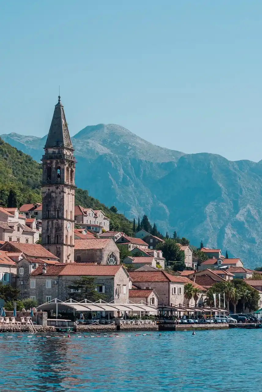 Church bell tower rising above the old town of Kotor with mountains behind