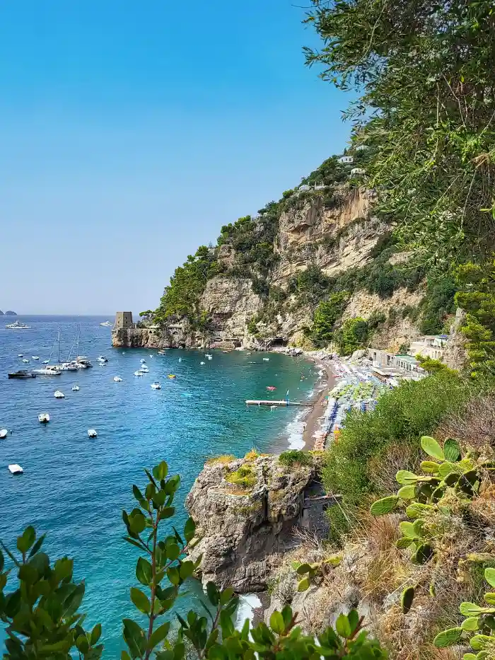 Turquoise cove with boats below the cliffs, among the best Amalfi Coast beaches