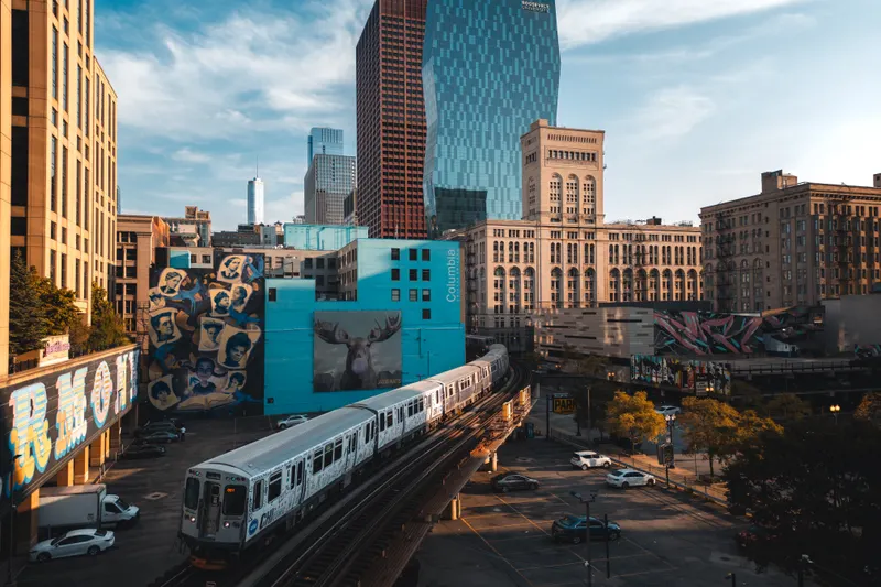 Chicago L train passing colourful street murals, like those around Wicker Park